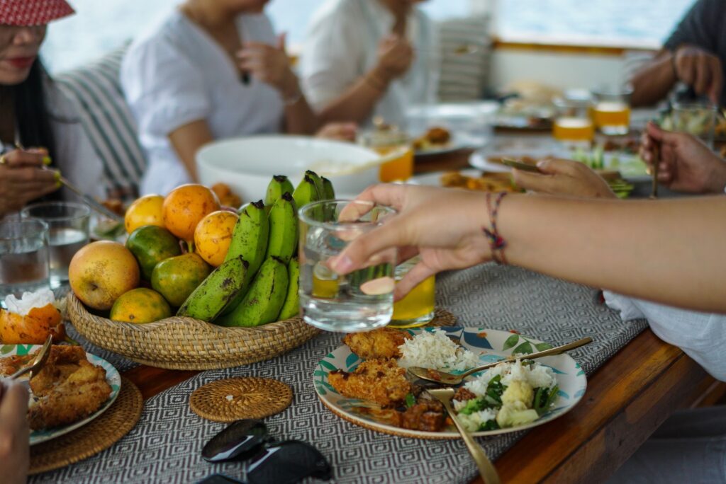 Woven fruit basket with bananas and oranges among plates of food on the dining table