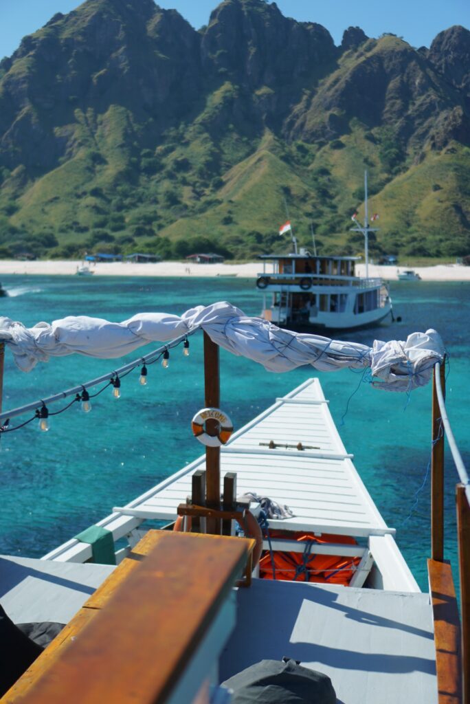View from Zendaya's bow toward jagged green peaks and turquoise water, another boat anchored near a white beach