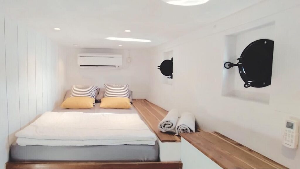 Superior cabin on Zendaya with a bed, mustard pillows, and round black porthole-style wall decor