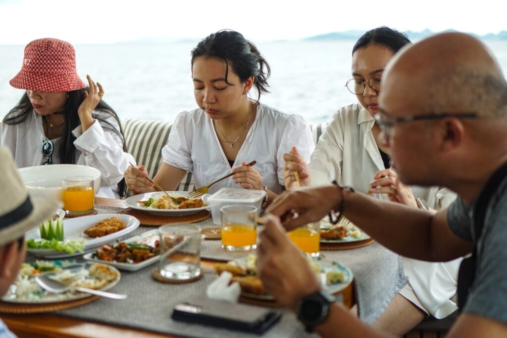 Guests seated at the dining table eating together with open water visible behind them