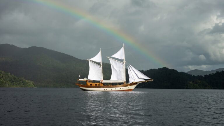 The Anne Bonny phinisi sailing under a rainbow on a Komodo liveaboard