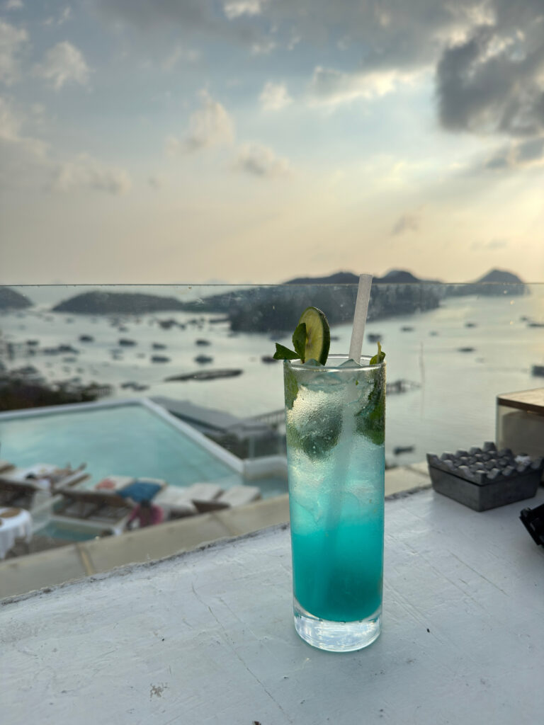 Cocktail on a rooftop ledge overlooking the Labuan Bajo harbour at sunset
