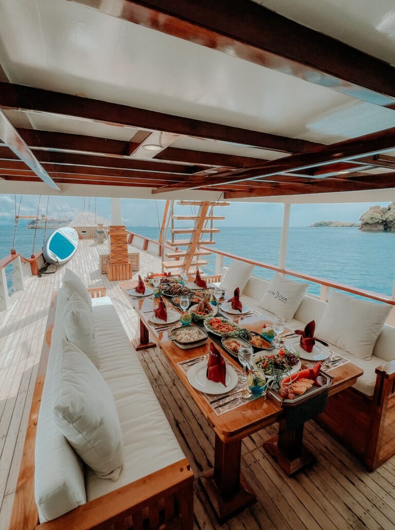 Outdoor lunch table set on the Gandiva deck with cushioned bench seating