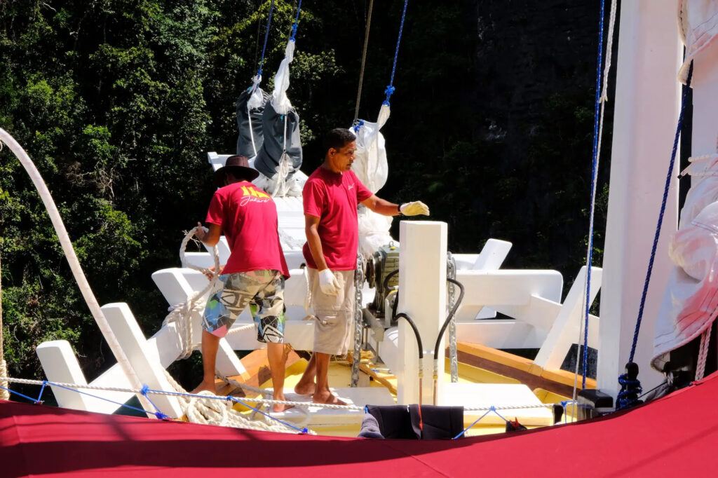 Crew members hoist a white sail aboard Jakare