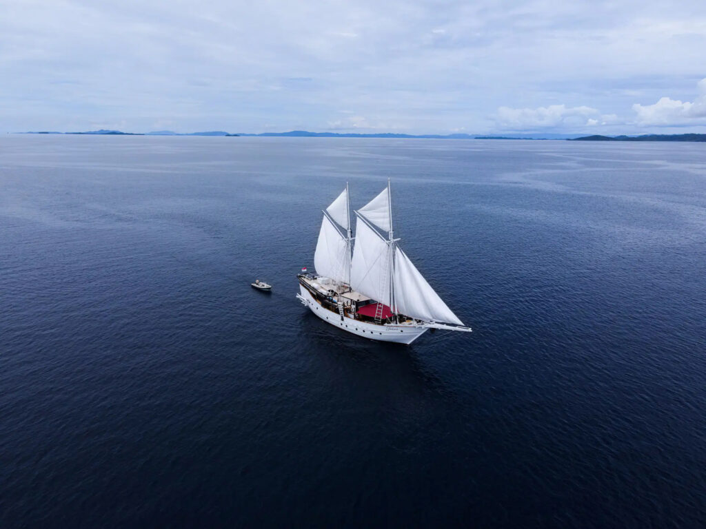 Jakare under full white sail on calm open water