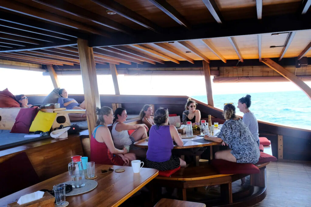 Guests gather around a table for a meal aboard Jakare