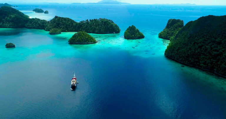 Jakare liveaboard anchored among limestone island clusters in turquoise water