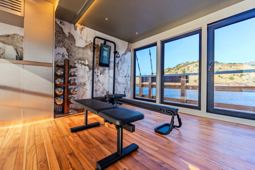 Gym bench facing a sea view window aboard Kayra