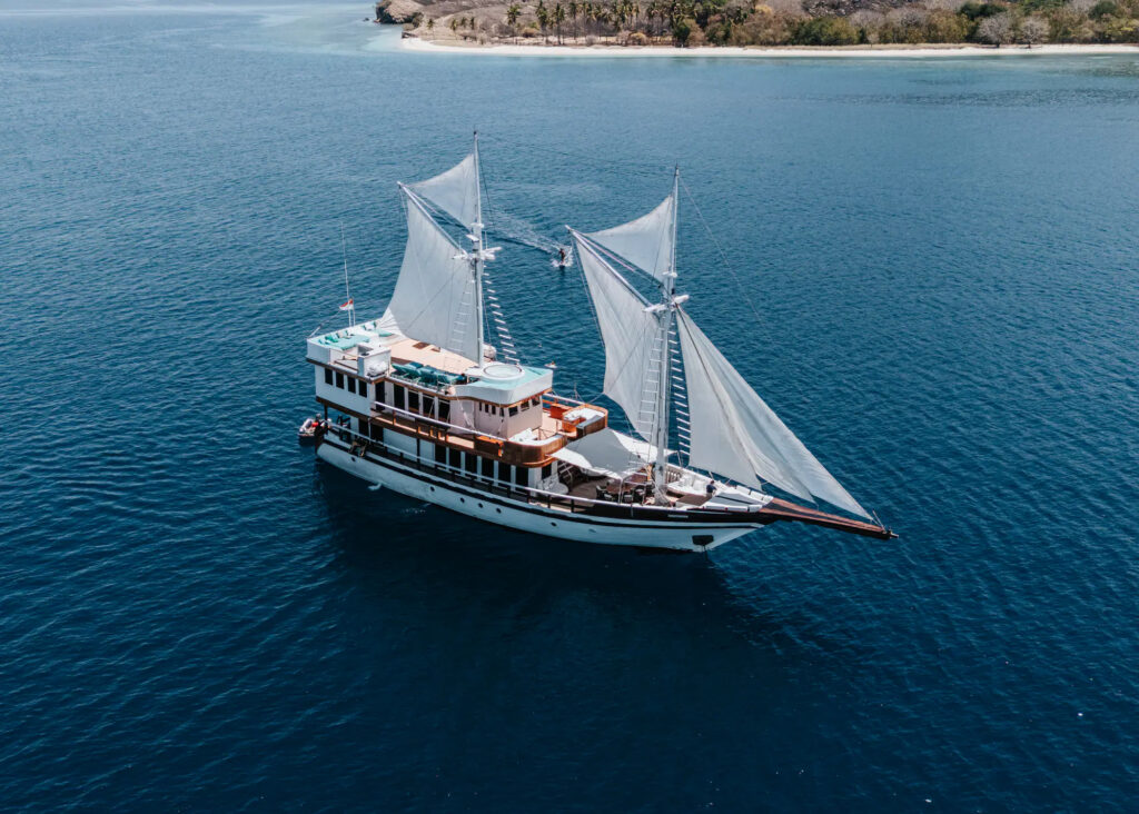 Kayra sailing close to a green coastline