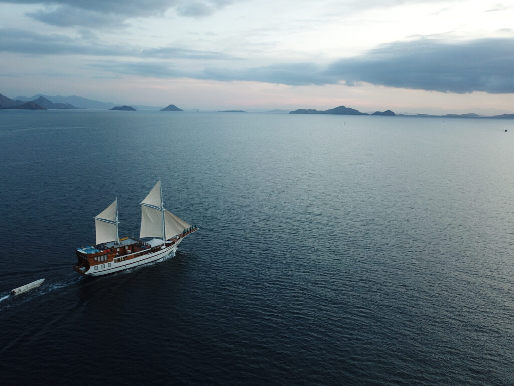 Lady Grace under sail at dusk with open water and distant islands