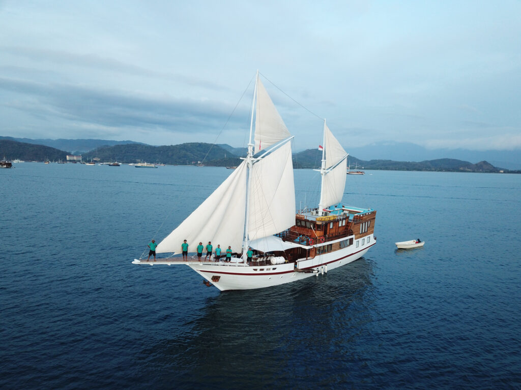 Lady Grace under full sail with crew on the bowsprit near the harbor