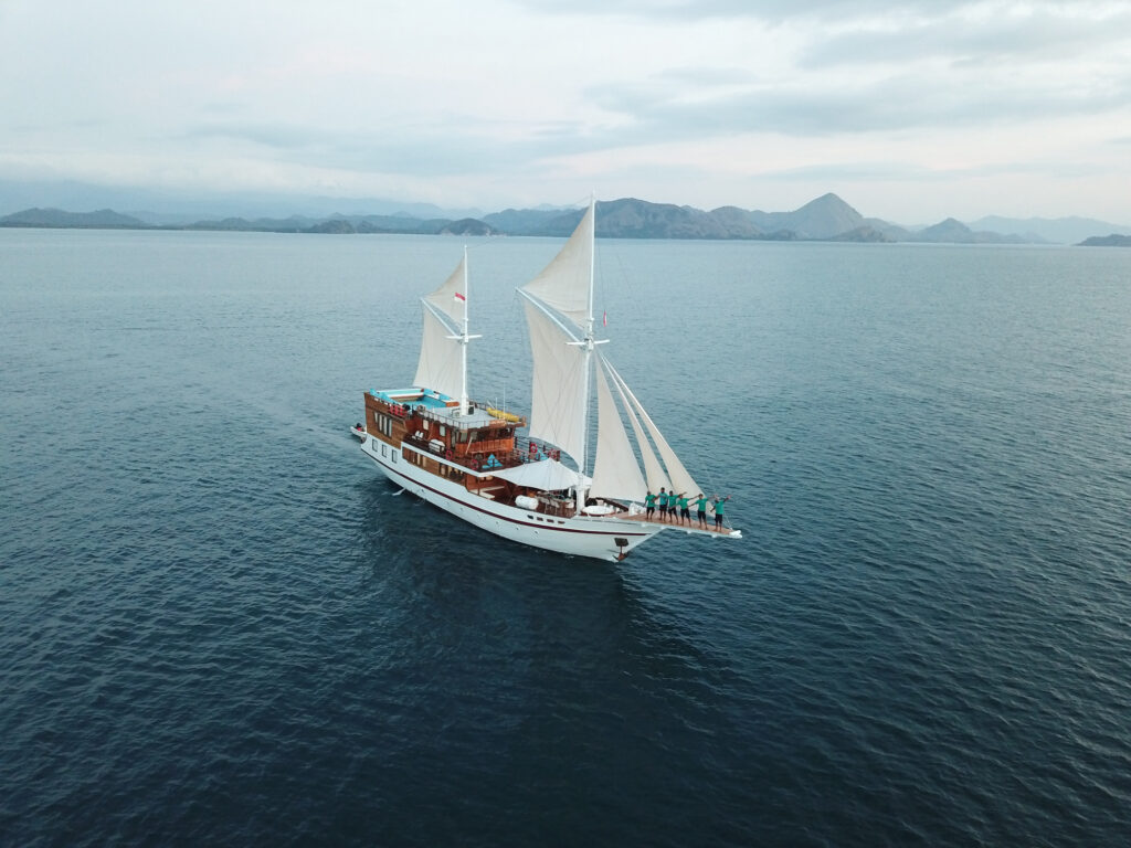 Lady Grace under full sail with crew on the bow under cloudy sky