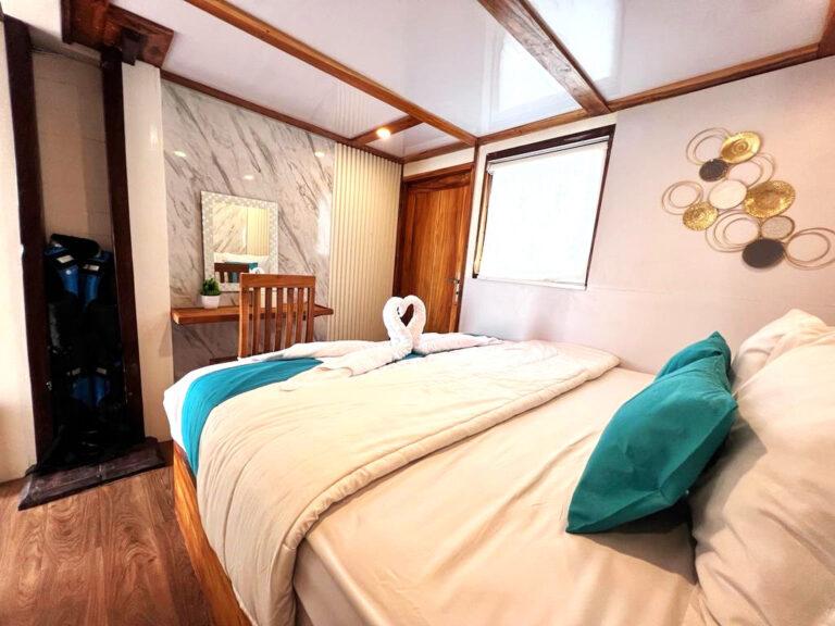 Kerang Cabin double bed with swan towel art and teal accent pillows