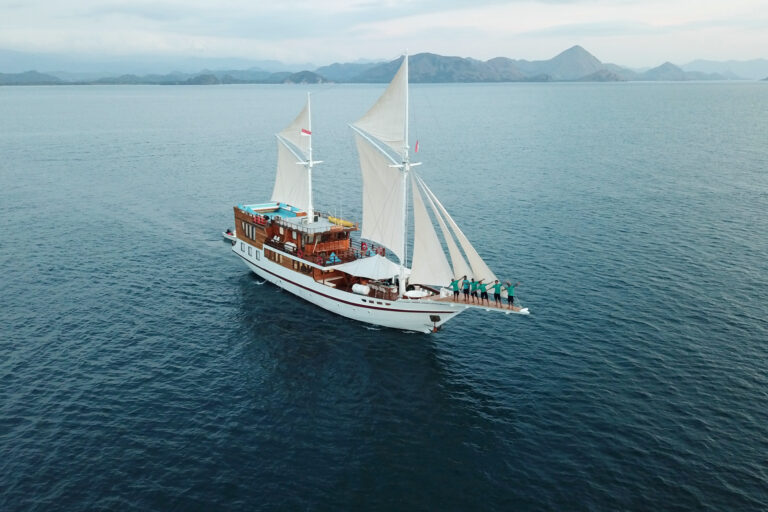 Lady Grace liveaboard phinisi under full sail with crew on the bow