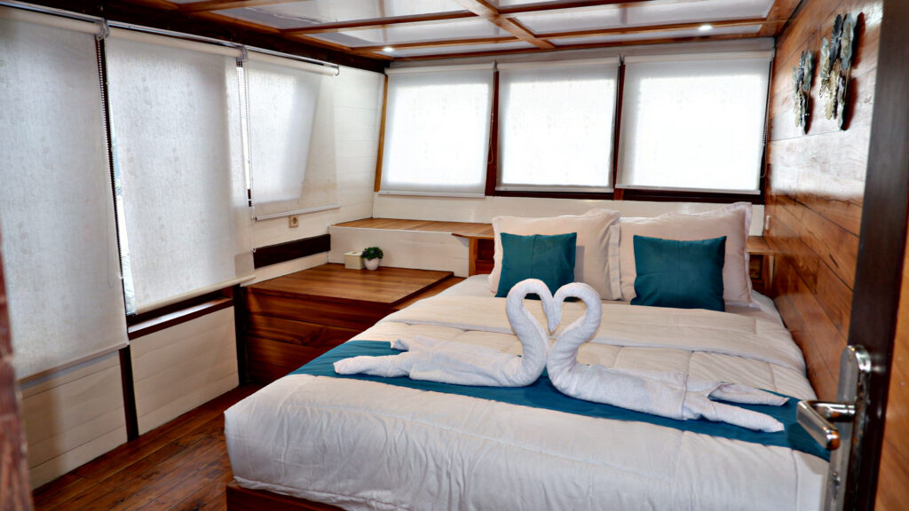Paus Cabin double bed with heart-shaped swan towels beneath wide windows