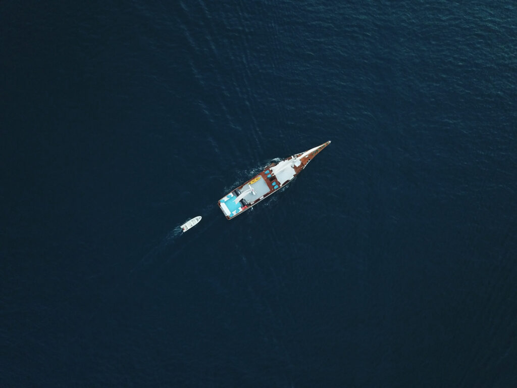 Top-down aerial view of the boat with its tender floating alongside