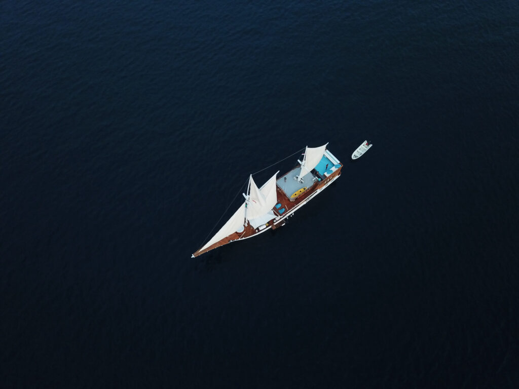 Top-down aerial view of the boat under sail with teal bean bags on deck
