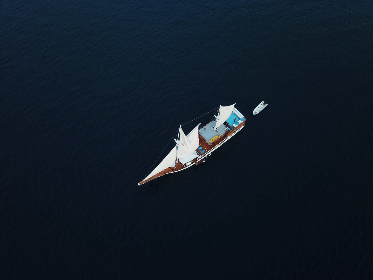 Top-down aerial view of the boat under sail with teal bean bags on deck