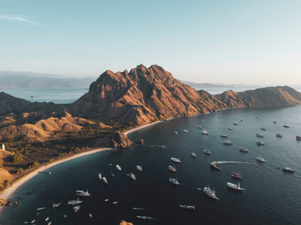 Aerial view of Padar Island ridge and bay with dozens of boats anchored at sunrise