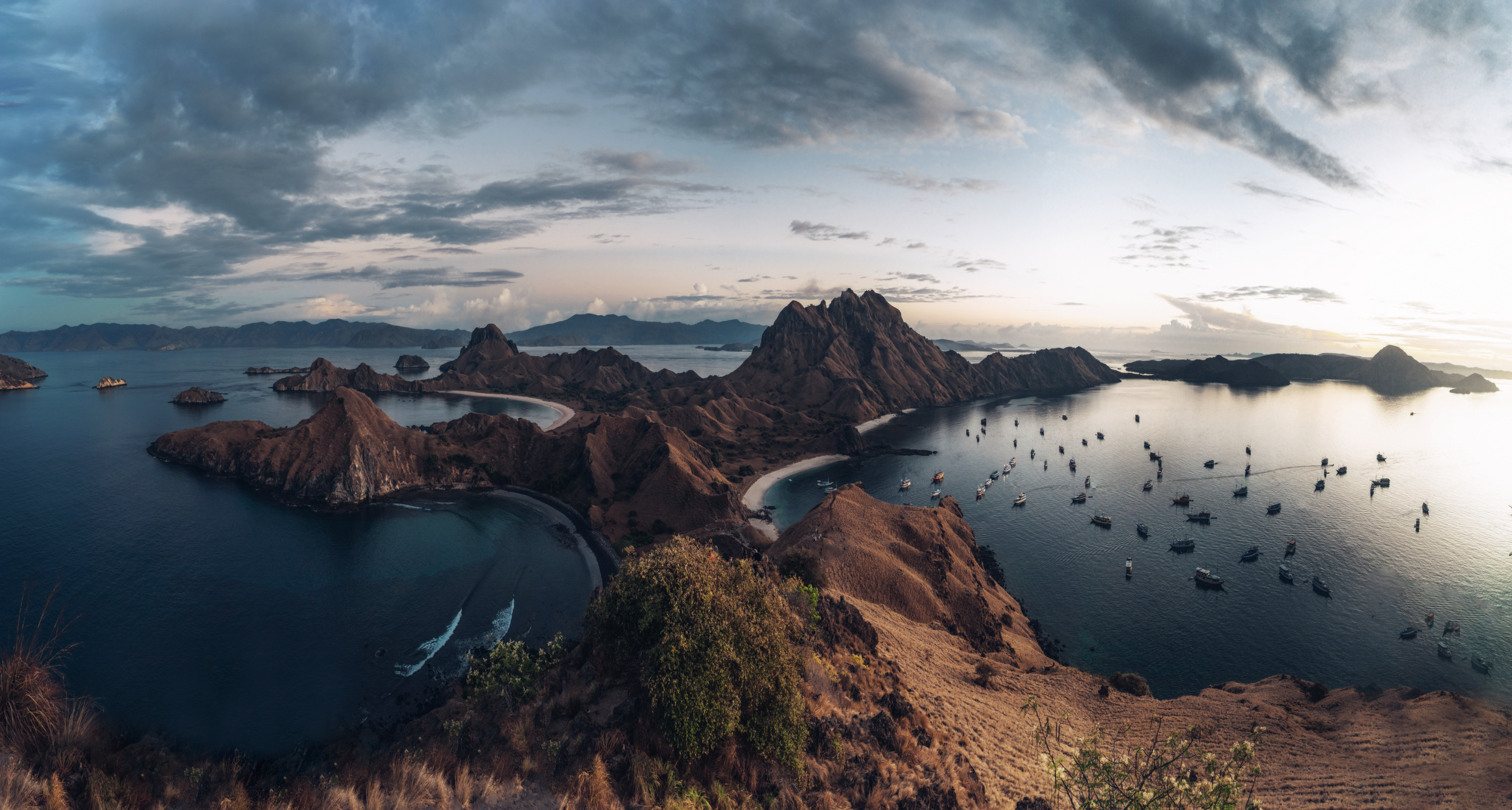 Kelor Island hilltop view over a white sand spit, anchored vessels and golden dry hills