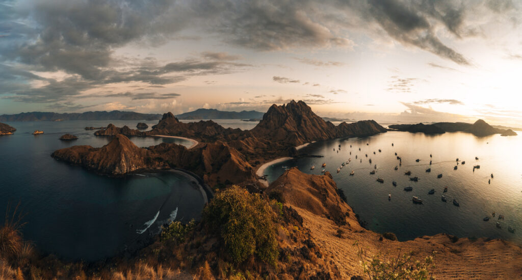 Sunset panorama from Padar Island ridge over its bays and an anchored fleet