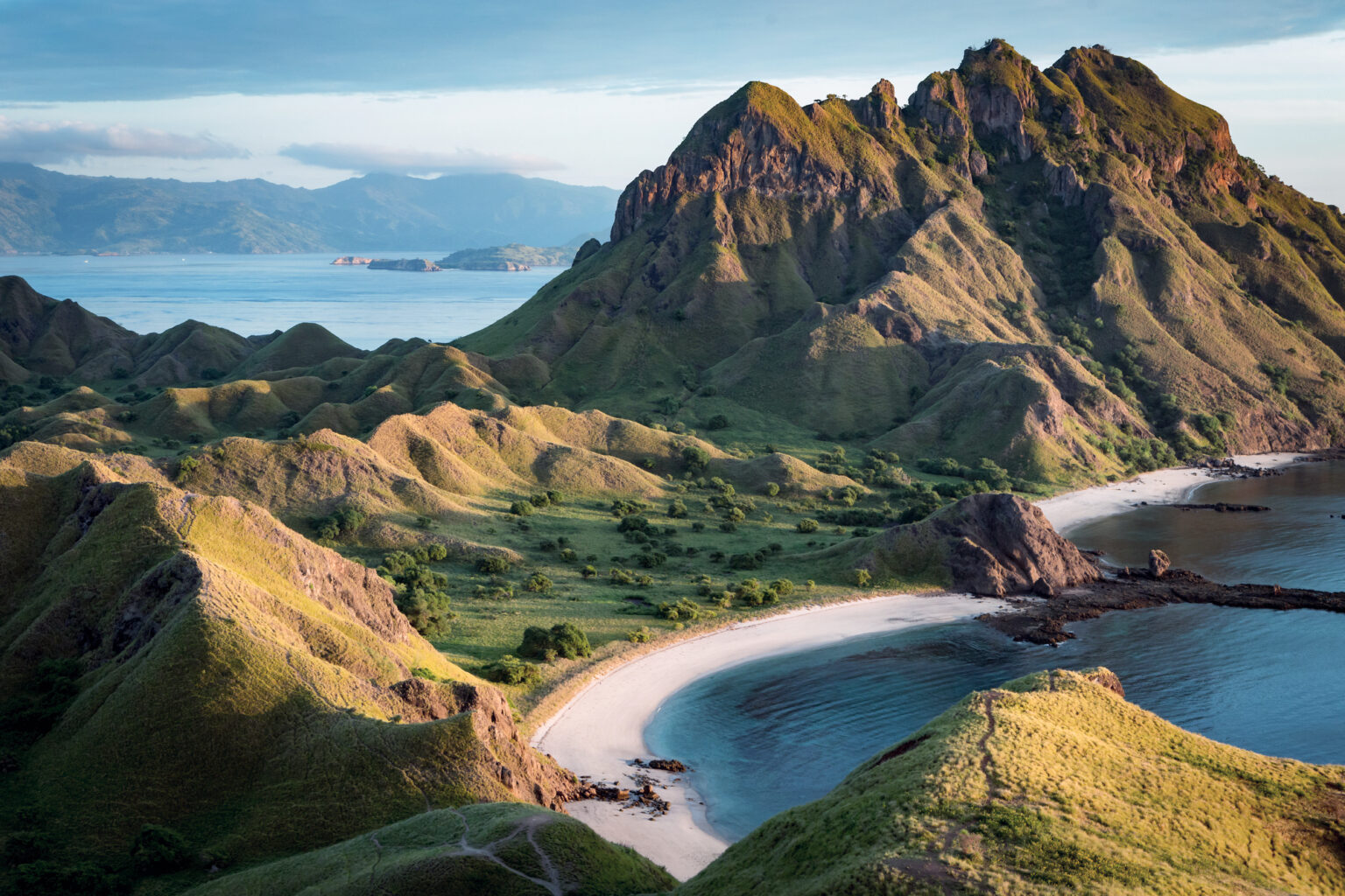 Padar Island viewpoint over green ridges and two curving bays in early light, Komodo