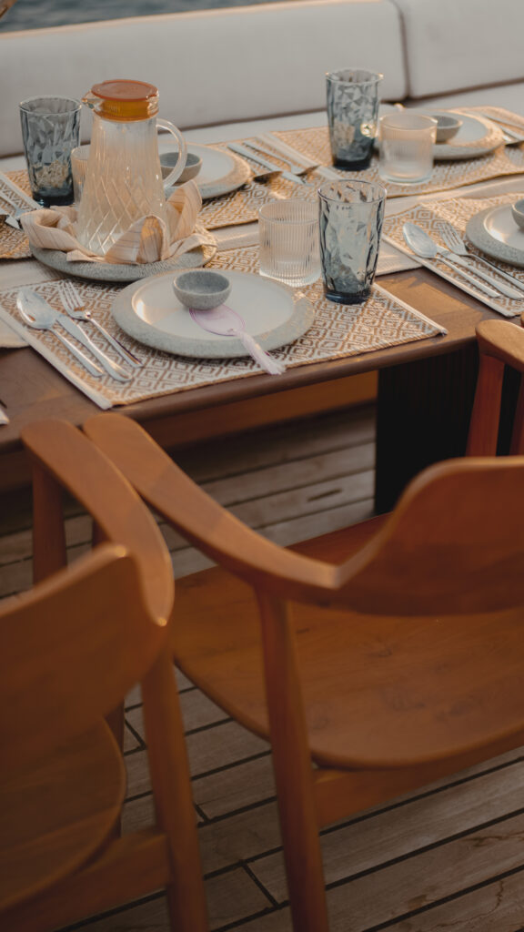 Alfresco table set with woven mats, glassware and a water jug on deck