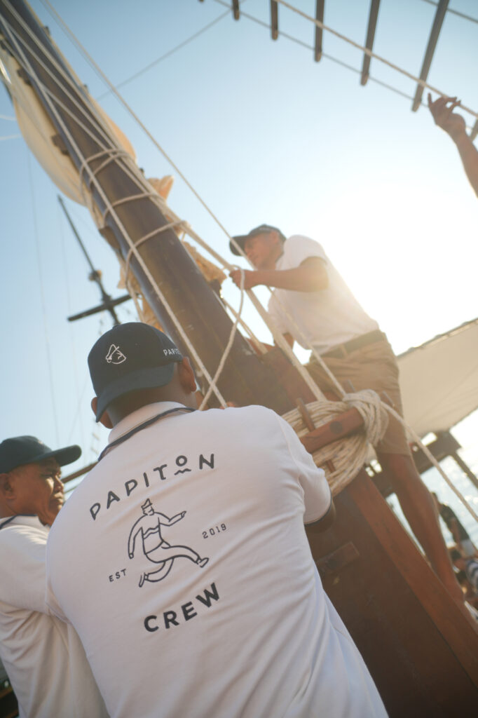 Papiton Allo crew hauling lines at the mast in bright midday sun