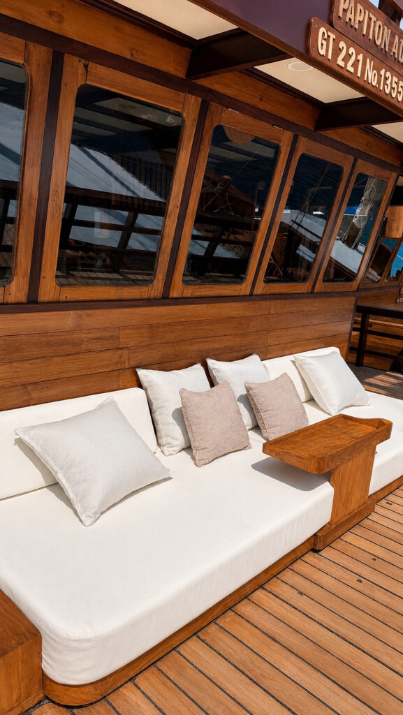 Cushioned deck daybed below the Papiton Allo name plaque and saloon windows