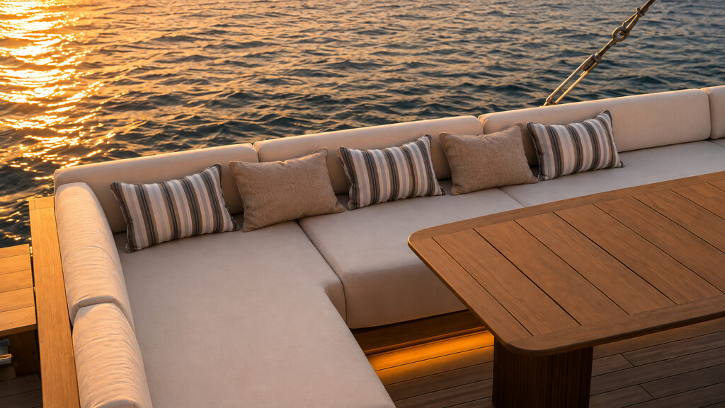 Top deck corner sofa and timber table with sunset light on the water behind