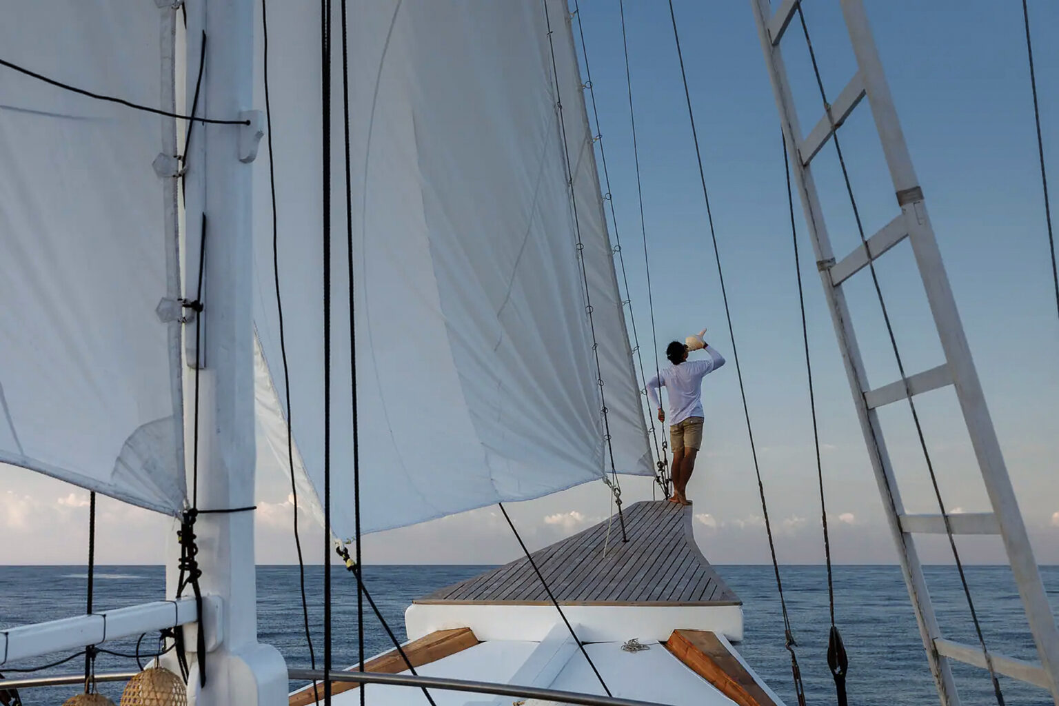 Traveler alone at the bow of a phinisi under sail on a private trip from Labuan Bajo