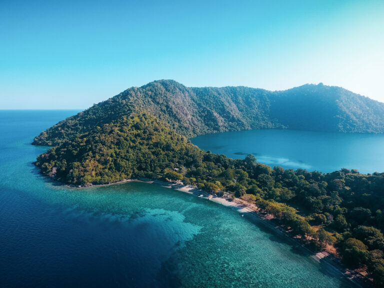 Forested Satonda Island with its enclosed crater lake and turquoise reef, from above