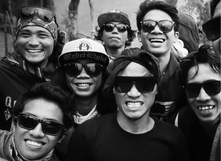 The Lostboys crew grinning in sunglasses in a close black and white group selfie