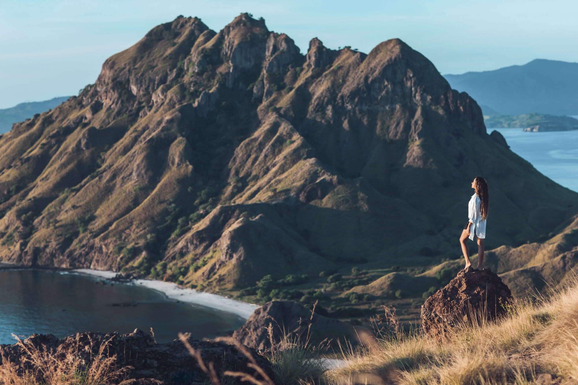 Wide dawn panorama from Padar Island's summit over three bays and anchored vessels, Komodo