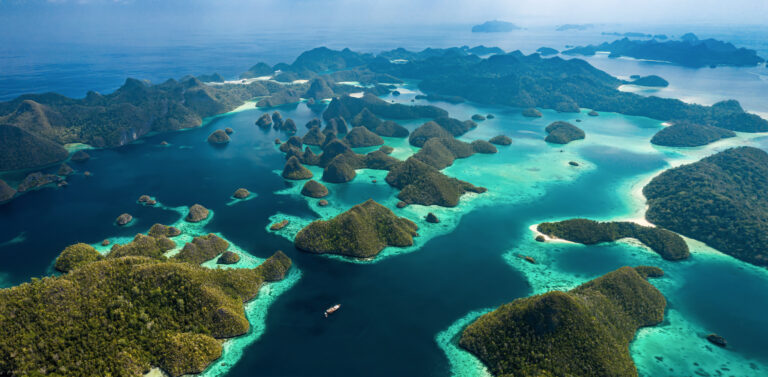 Raja Ampat liveaboard anchored among the Wayag karst islands and turquoise lagoons, aerial view