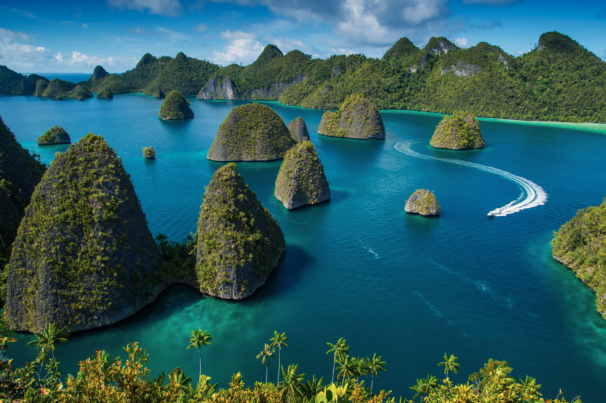 Wide dawn panorama from Padar Island's summit over three bays and anchored vessels, Komodo