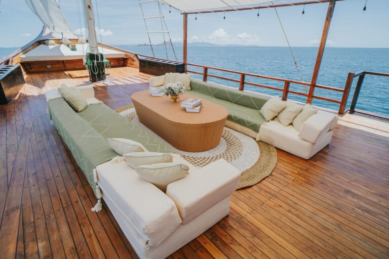 Shaded upper deck lounge on Zada Nara with sage cushions and a round wood table